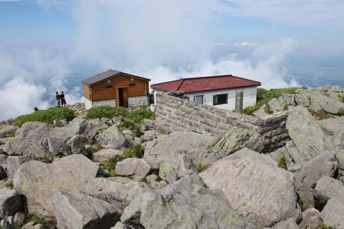 山頂避難小屋の向こうに雲湧く津軽平野を望む
